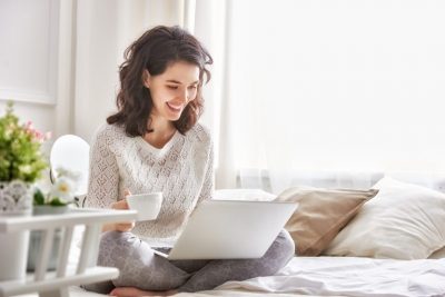 Lady sitting on her bed checking her insurance covers working from home