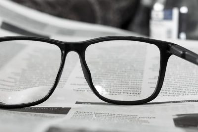 Reading glasses placed on a newspaper reporting equity release rate increase and rural properties in high demand after lockdown