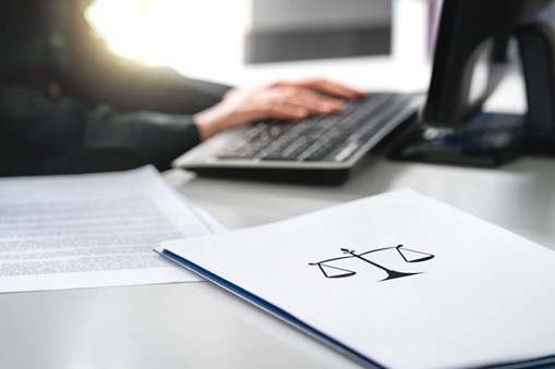 Business person working at a computer with a legal folder on the desk in foreground, LPA overhaul